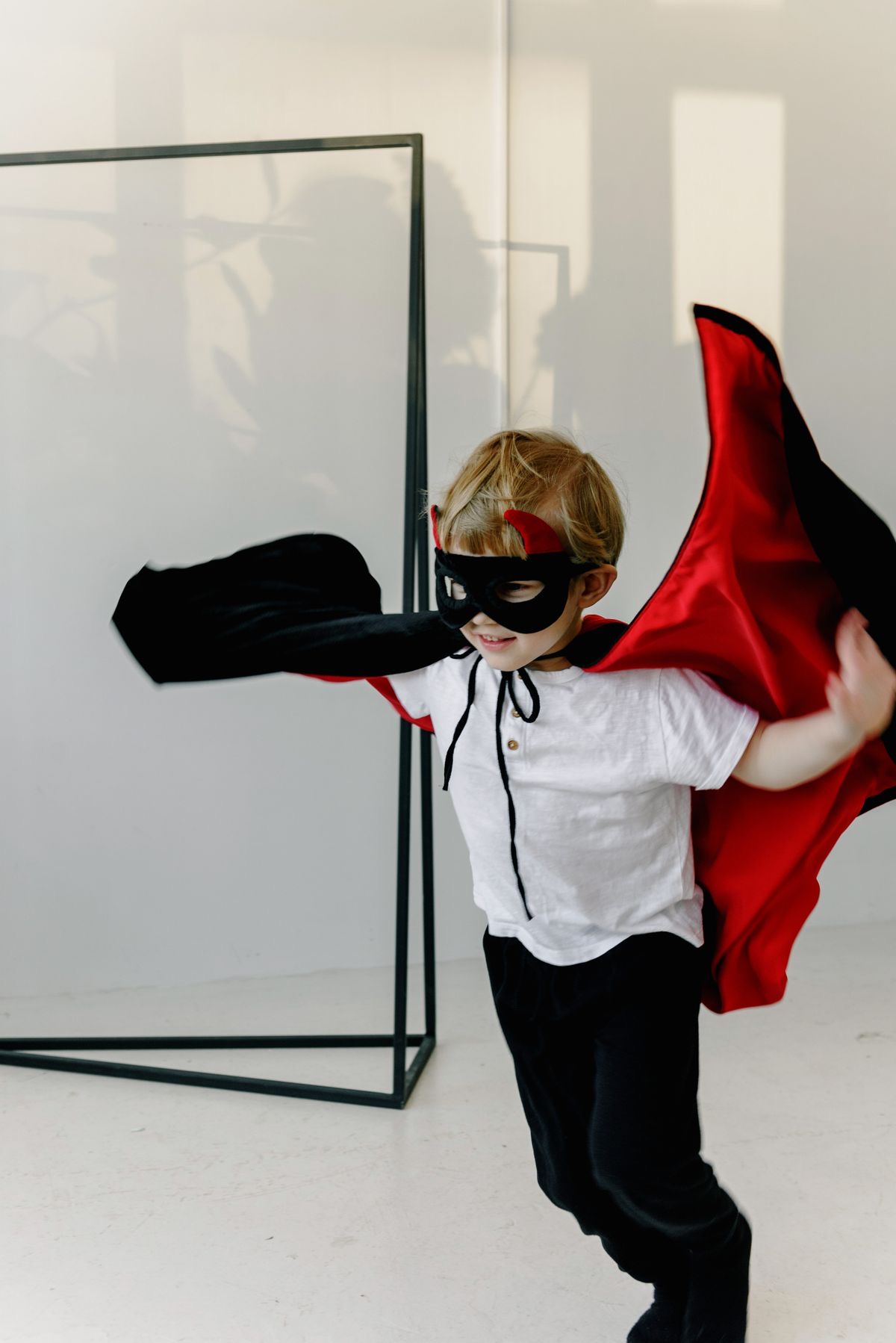 Child in a superhero cape striking a confident pose for the camera
