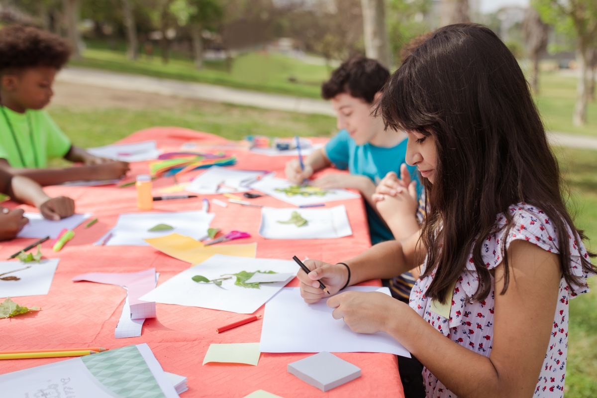 Kids making arts and crafts together at a camp activity table
