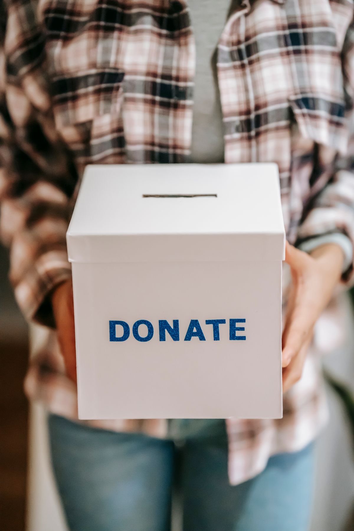 Hands holding a white donation box