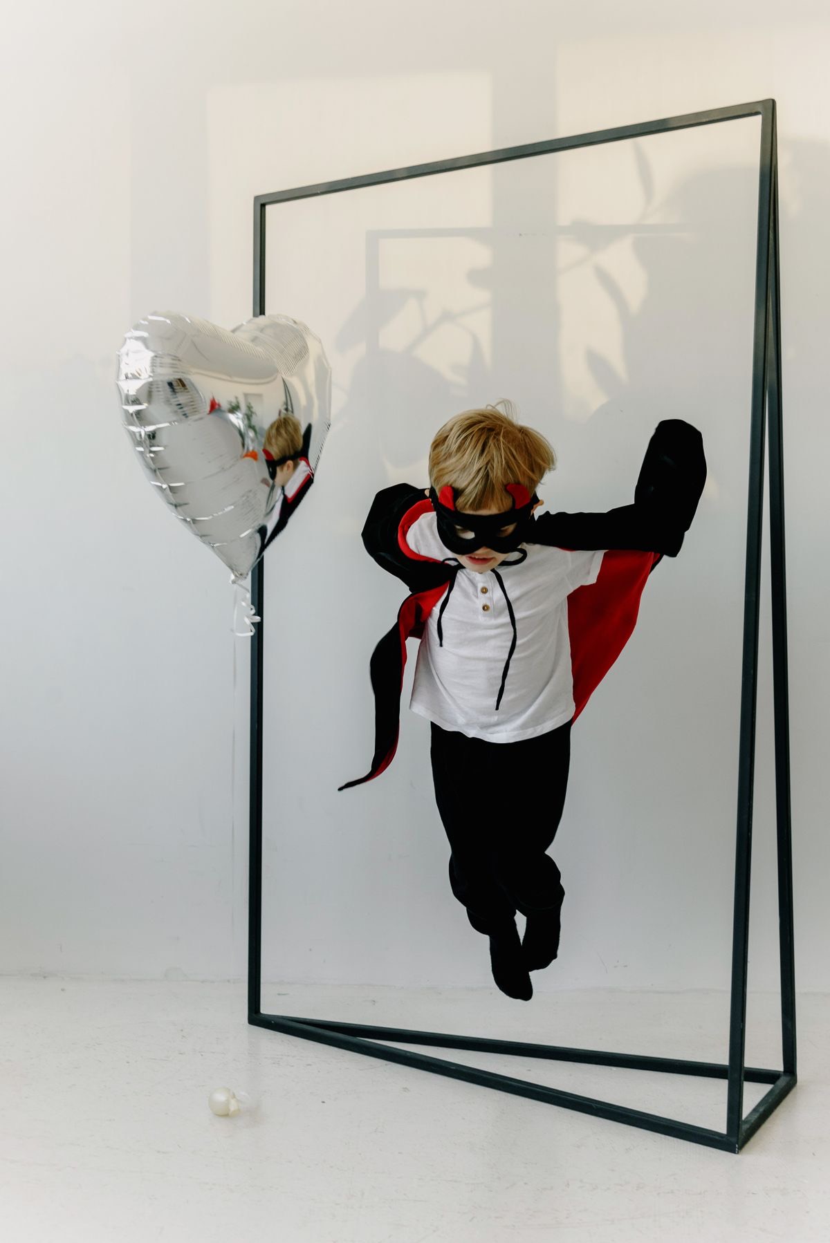Child striking a superhero pose in a flowing cape