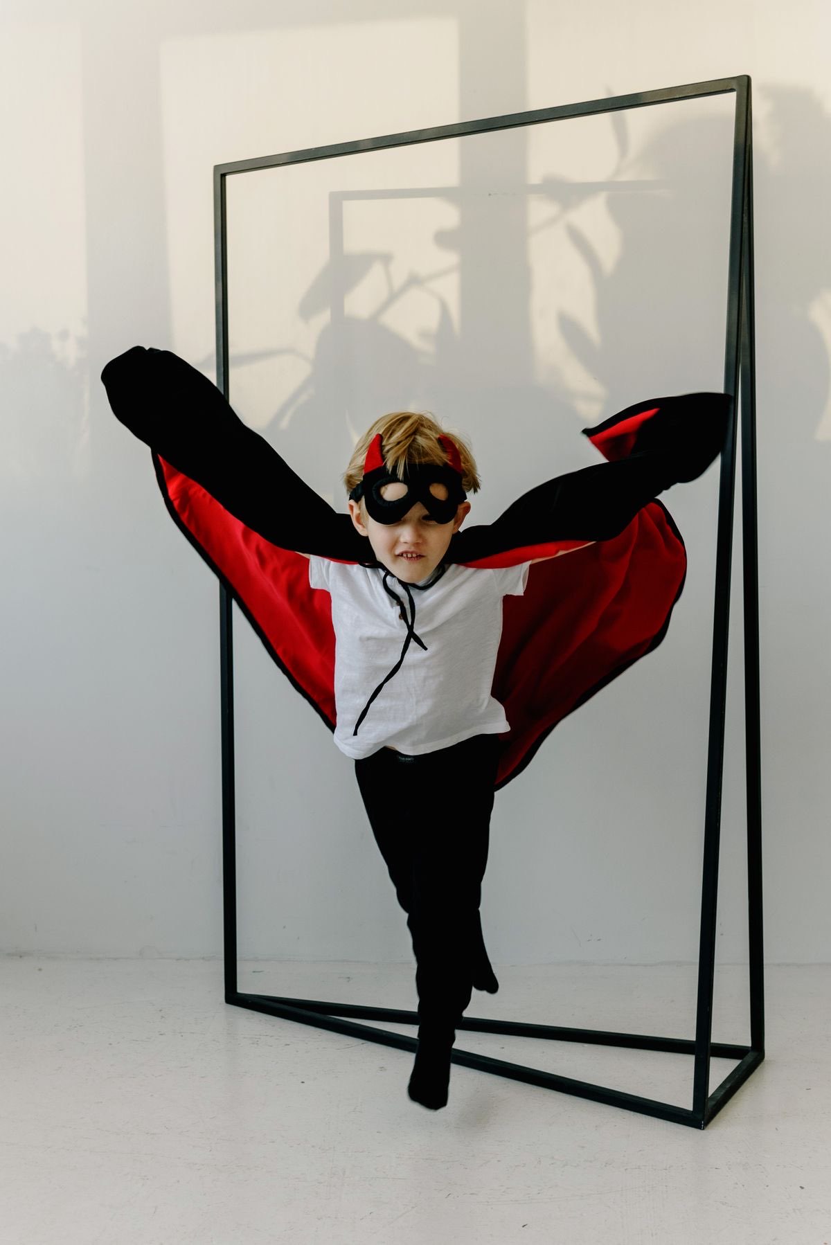 Child in a superhero cape posing for a portrait poster