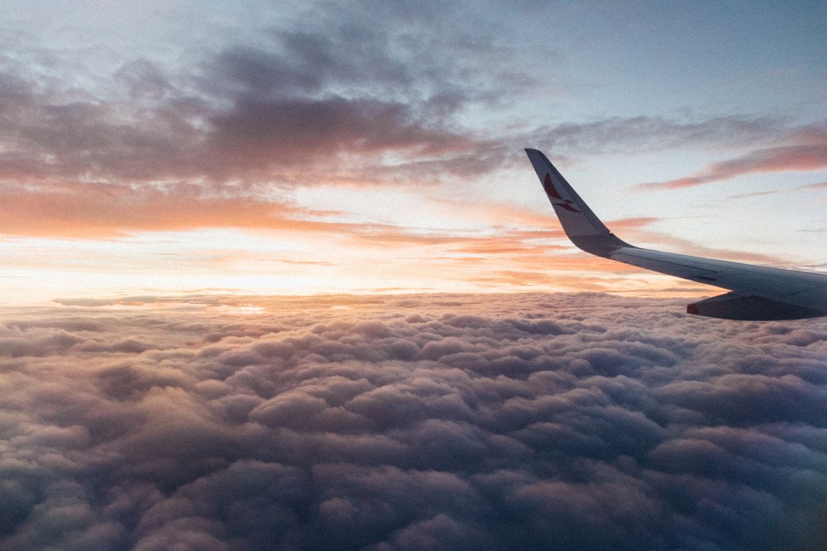 View from an airplane window above the clouds at sunrise