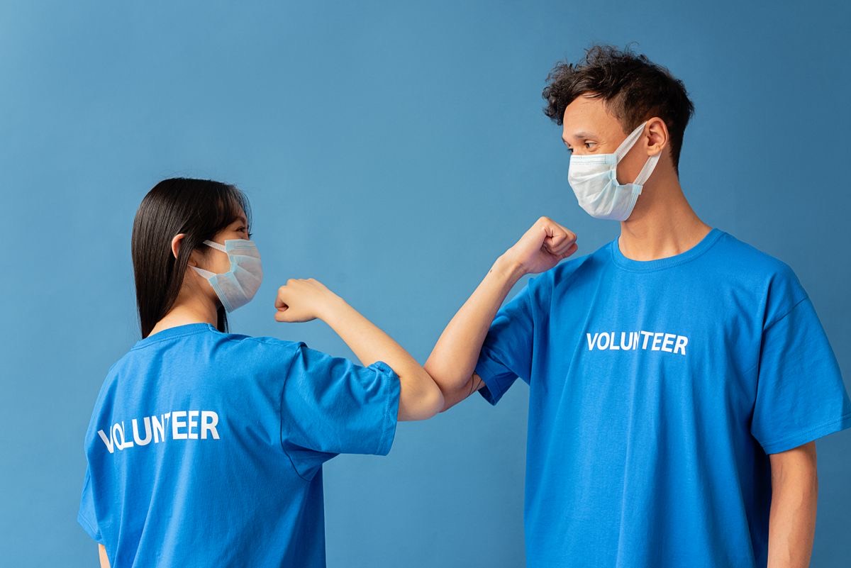 Two volunteers in matching shirts greeting each other at an event